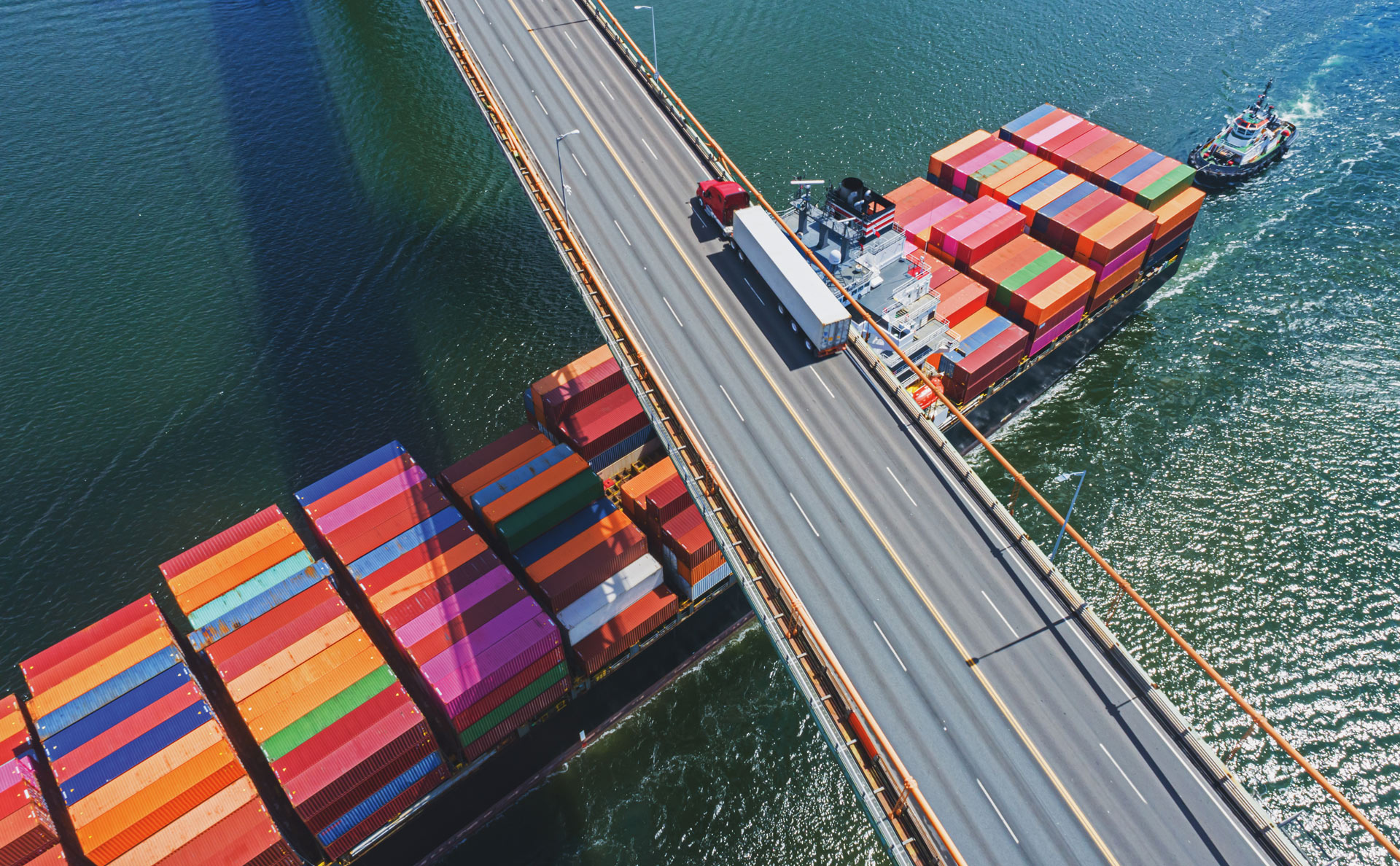 Das Bild zeigt ein Containerschiff, das unter einer Brücke hindurchfährt